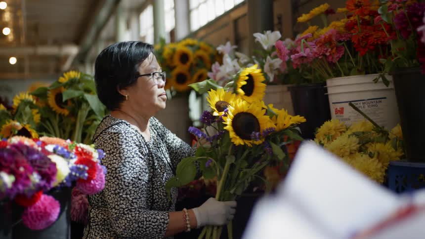 A woman puts together a bouquet of flowers