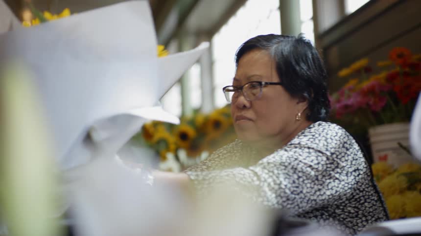 A florist places a finished bouquet of flowers in a display