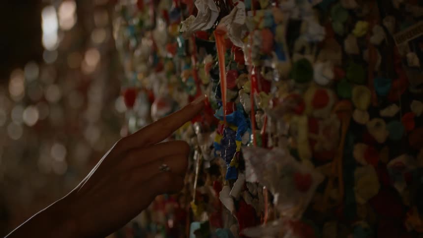 A woman touches an art installation on a wall made up of several small colorful pieces