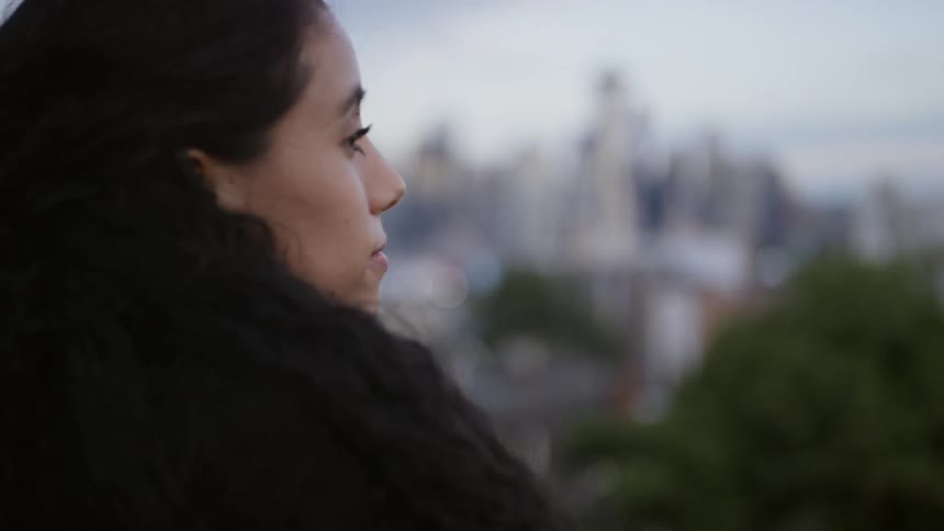 A woman overlooks the city skyline from a neighborhood