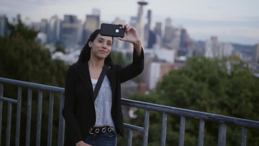 Woman takes selfie with city in background