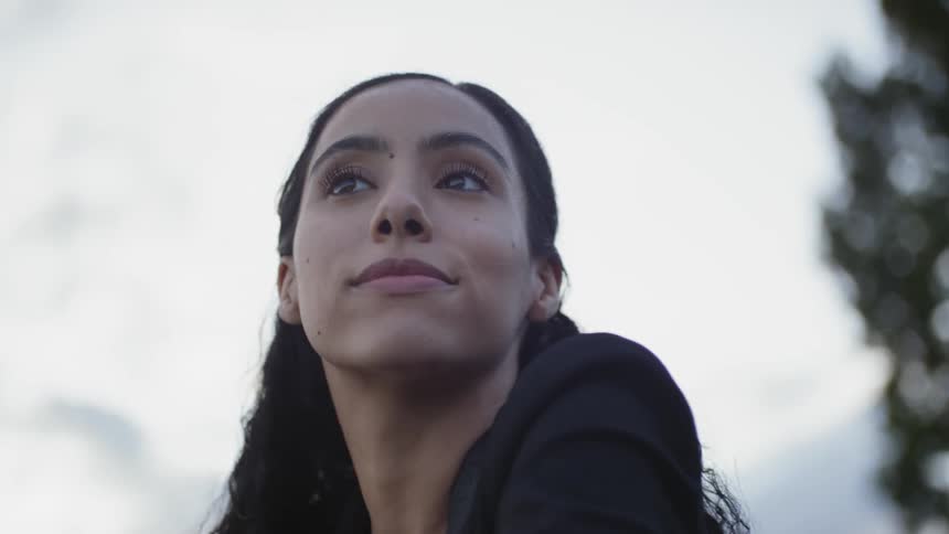 A woman looks around while standing outdoors and smiles