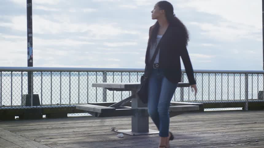 A woman walks around a seat on the pier