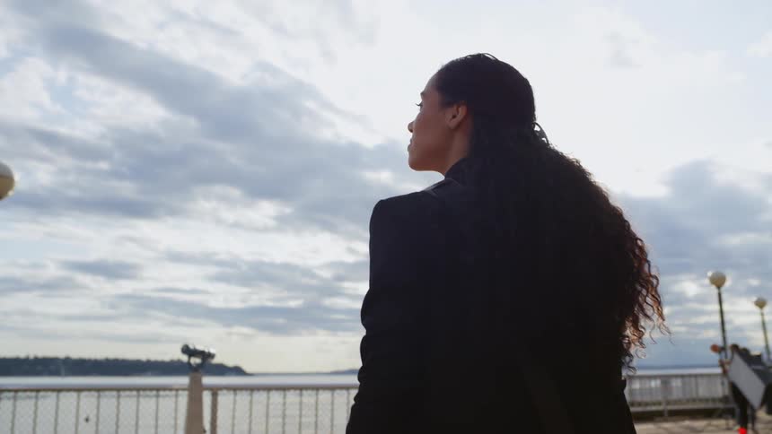 A woman walks on a viewing platform on the coast