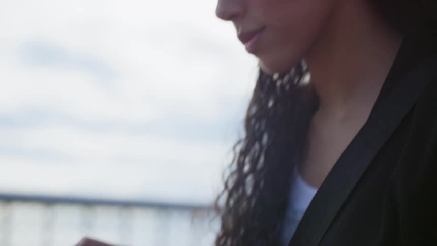 A hispanic woman fiddles with her smartphone outdoors