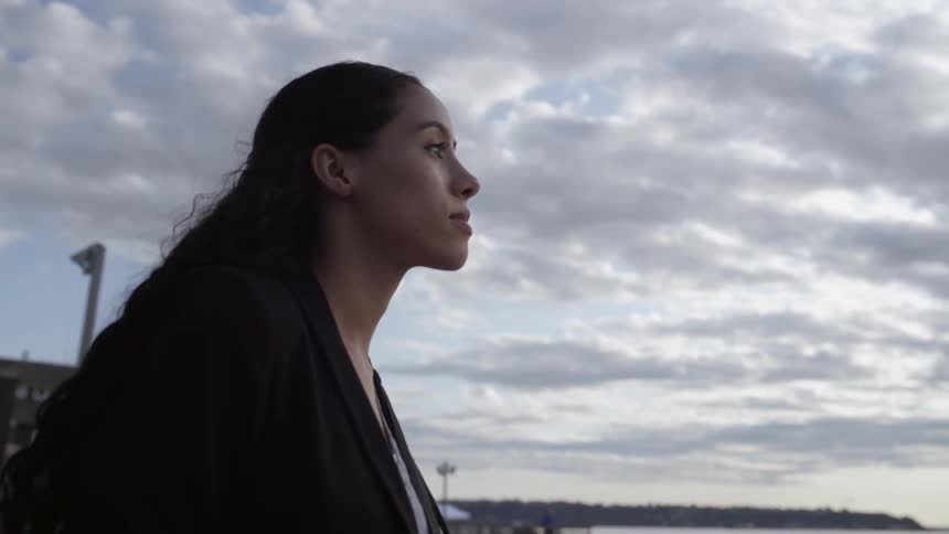 A woman is walking by the shore on a cloudy day