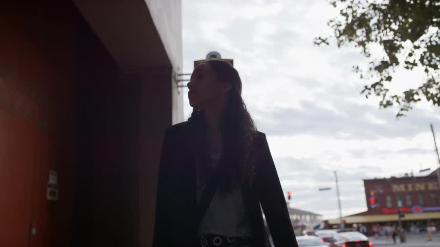 Woman walks next to building away from busy street corner