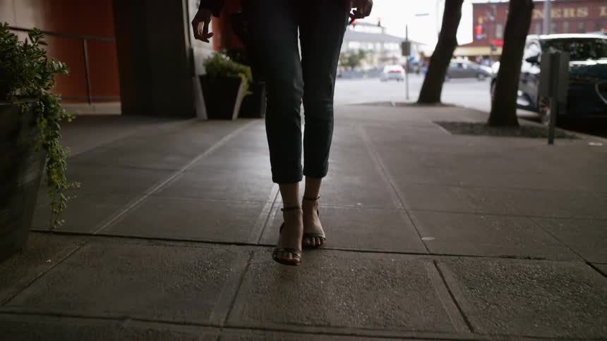 Woman walks down sidewalk in sandals