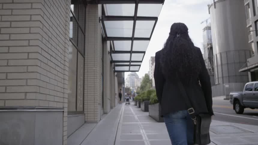 Curly hair brunette woman walks on the pavement in the city
