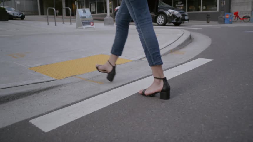 Woman walks across crosswalk in downtown