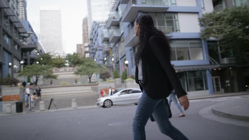 A young woman crossing a street in a city during the day