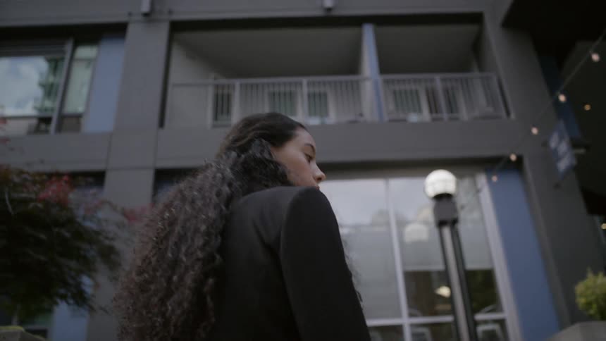 A woman walks towards the apartment building