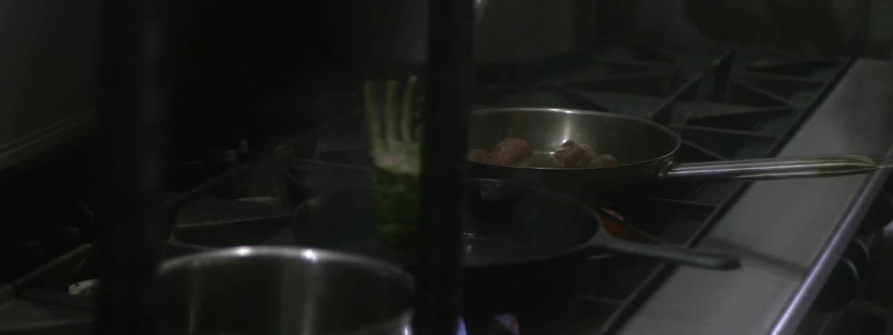 Close shot of someone using tongs to flip meat in a frying pan