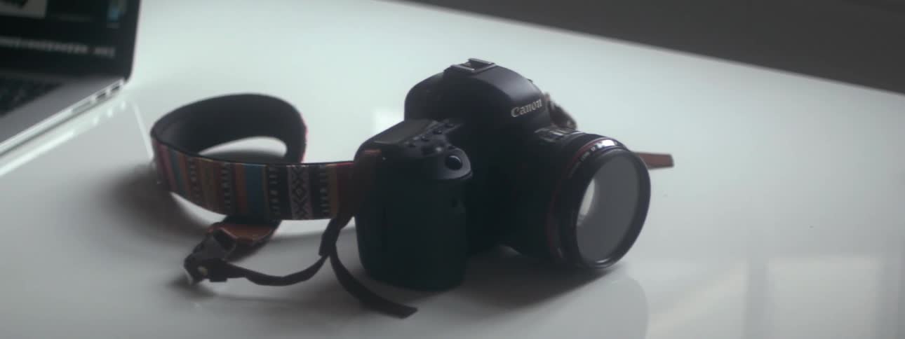 View of a camera and laptop on a white desk