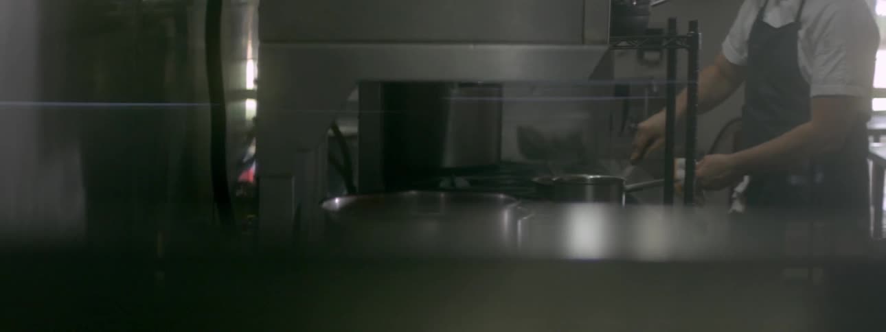 A man is cooking and preparing meals in a commercial kitchen