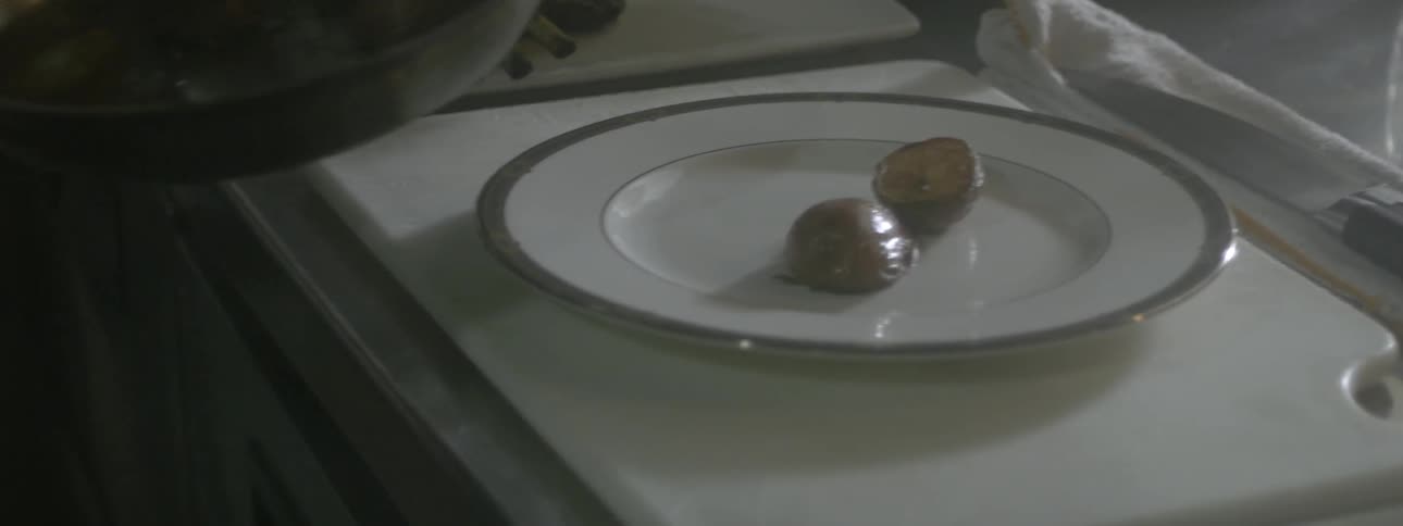 A man arranges small potato halves onto a dinner plate using tongs