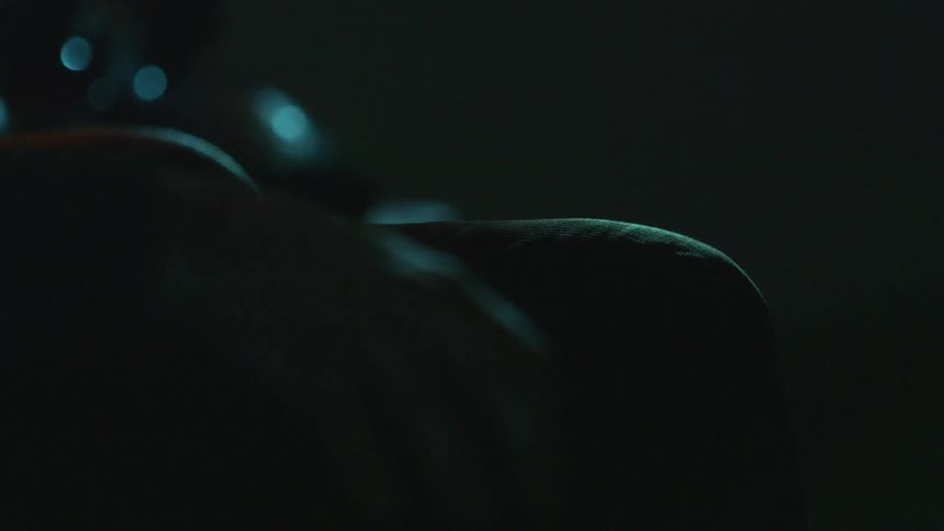 A person in the dark with their hands on their knees