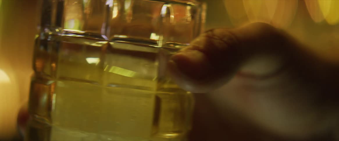 A man swirls a drink in a short glass