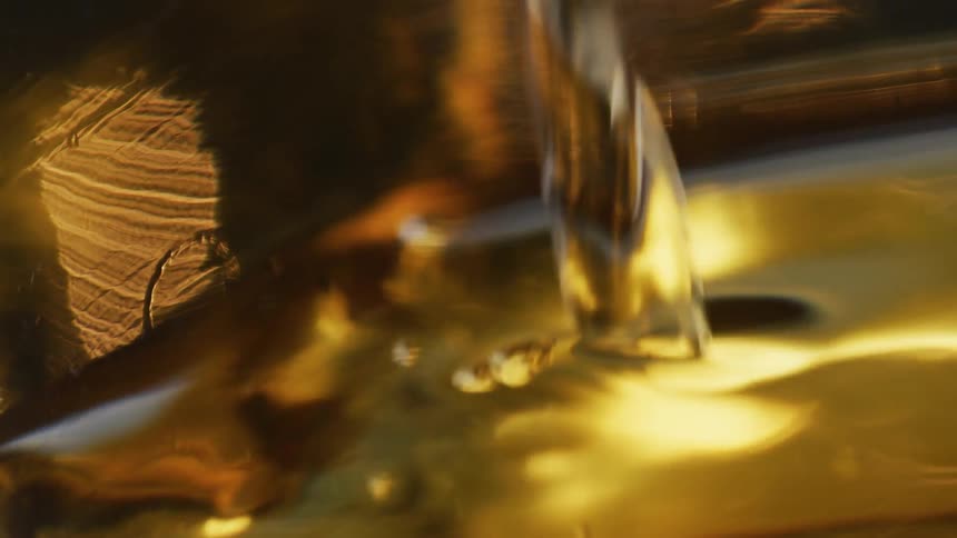 Gold yellow liquid is poured into a container