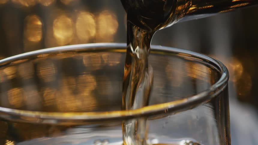 Liquid is poured into a glass from a bottle