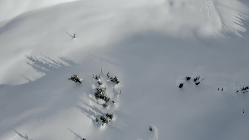 From high above a daring skier can be seen swiftly making their way down a snowy mountain