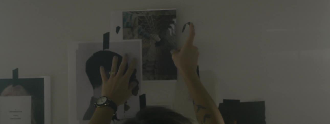 A woman tapes a picture to the wall