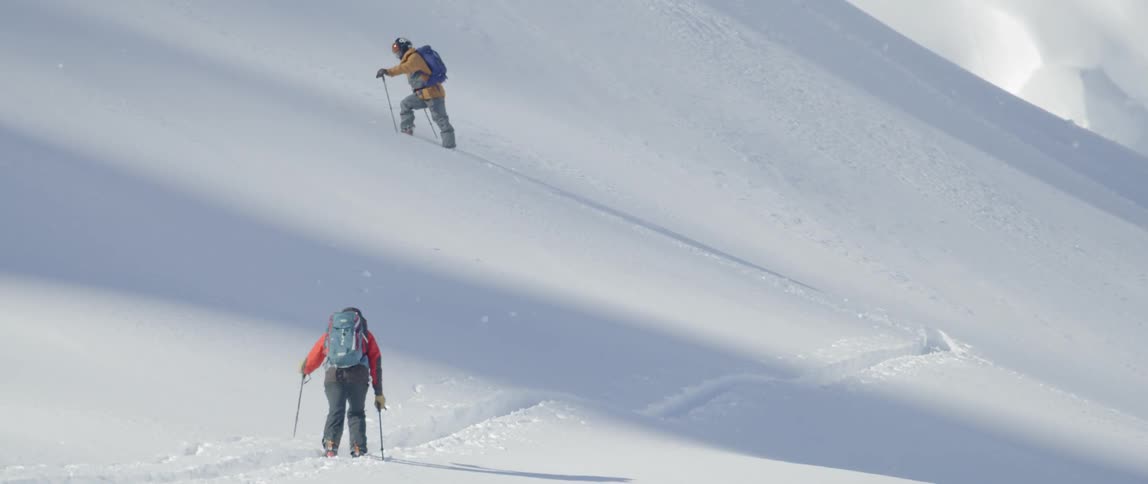 Two people are skiing up a mountain