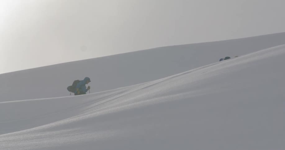 Two people hike on the snow covered hills