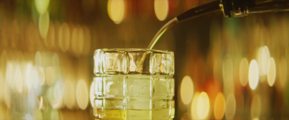 Liquor bottle pouring liquor in a glass with ice