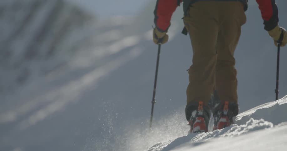 A skier walks across a snow covered mountain with a large backpack