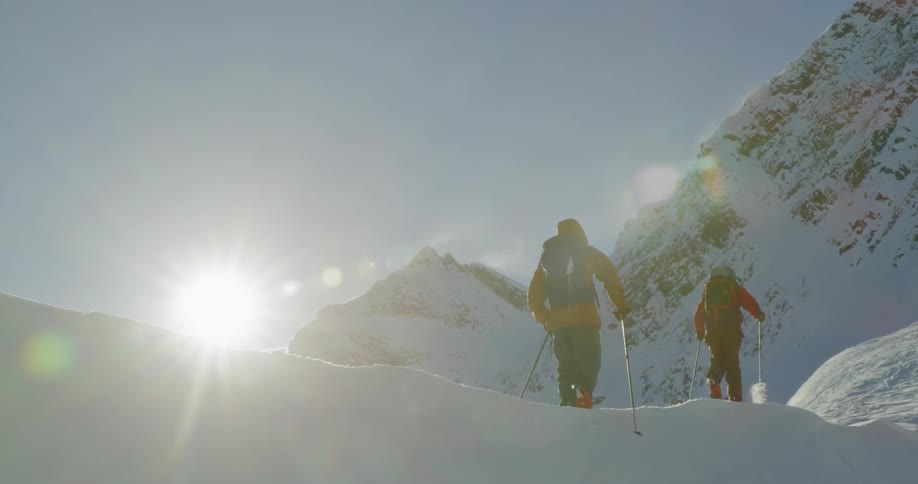 Two people snowshoe near a mountain