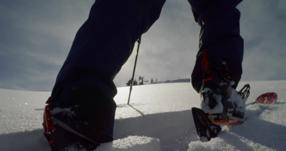 A foot with snowboard walks in the thick snow