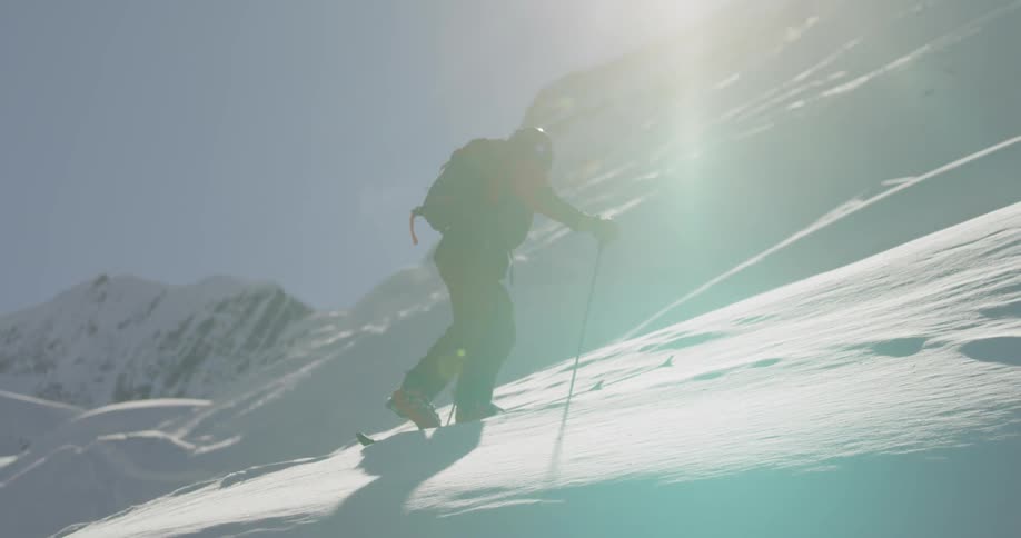 A man is hiking up a snow covered mountain slope