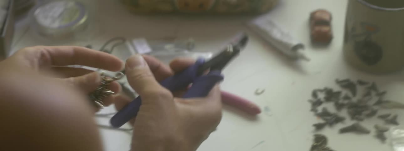 A woman is using pliers to make jewelry