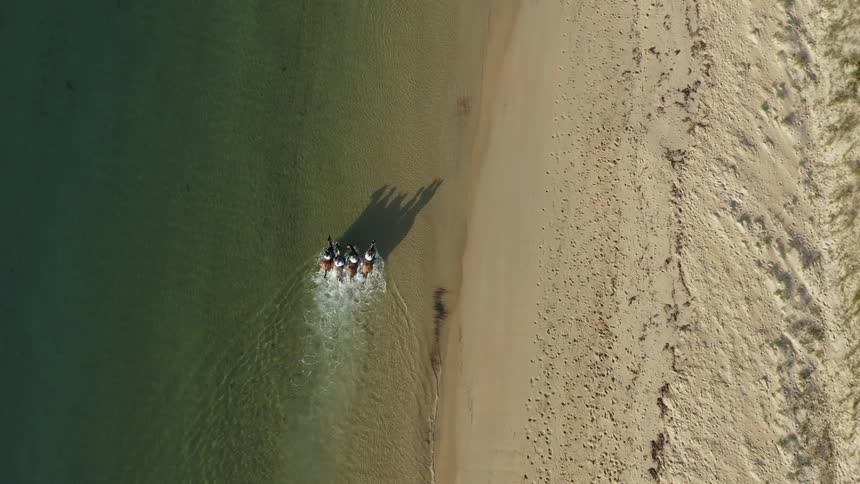 The people ride horses in the water below