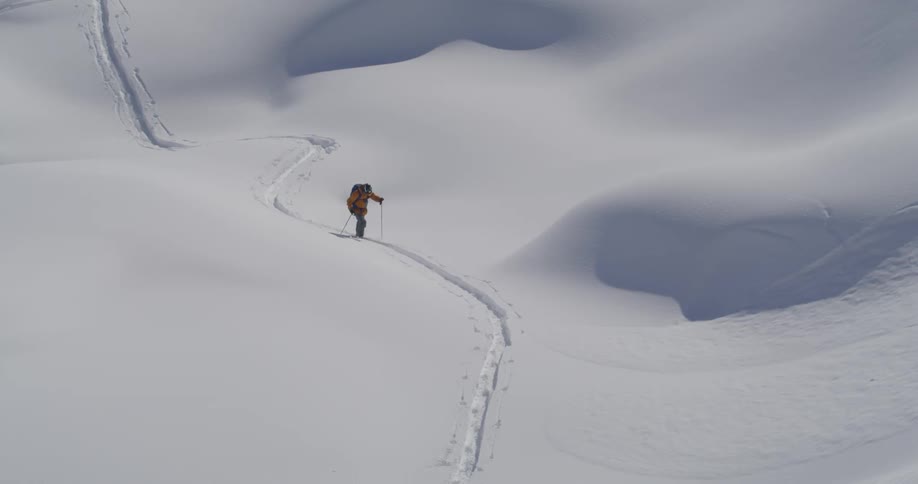 A man with red jacked walks on the snowy mountain
