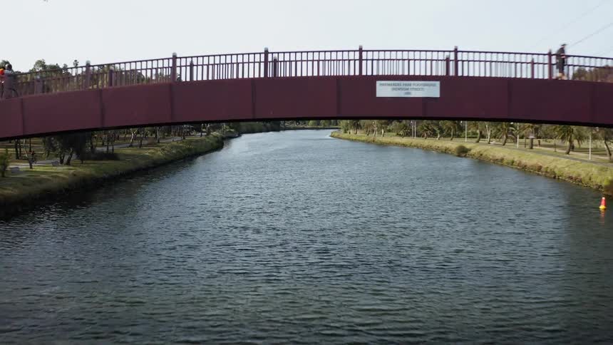 A man is jogging over a bridge as a river is flowing downward