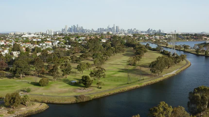 The trees and river are overlooked by the city skyline