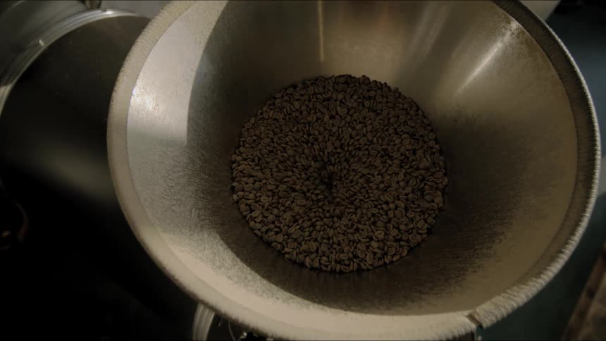 Coffee beans draining into a coffee roasting machine hopper
