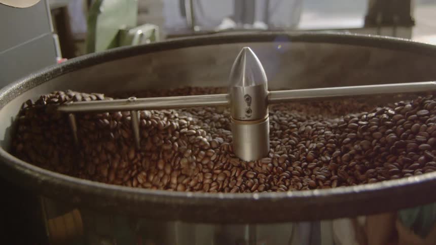 Machine arms stir coffee beans roasting and drying  in roaster