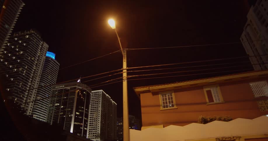 Traveling past homes with city buildings behind at night