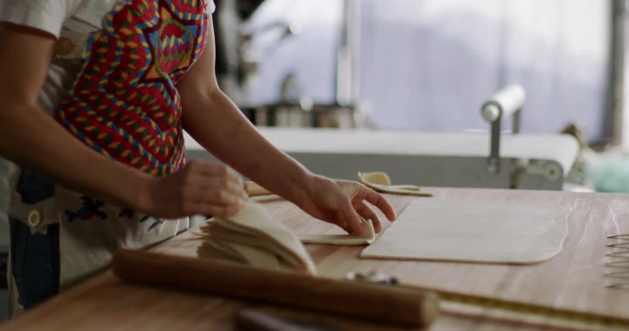 A woman stacks dough cut in triangle shapes