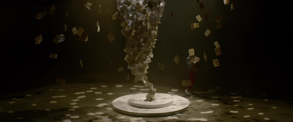 Woman walks around modern art piece surrounded by hanging paper