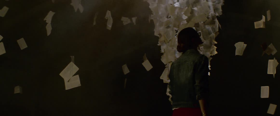 A woman looks at papers floating around the room
