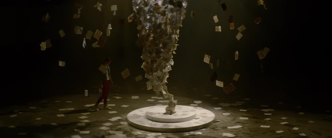 A woman walks around a large paper art structure