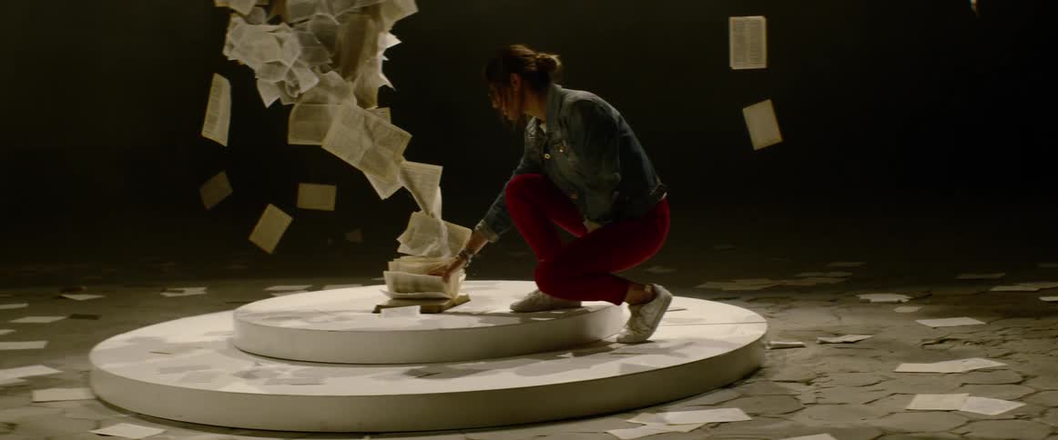 A young woman in red pants walks up to an art exhibit