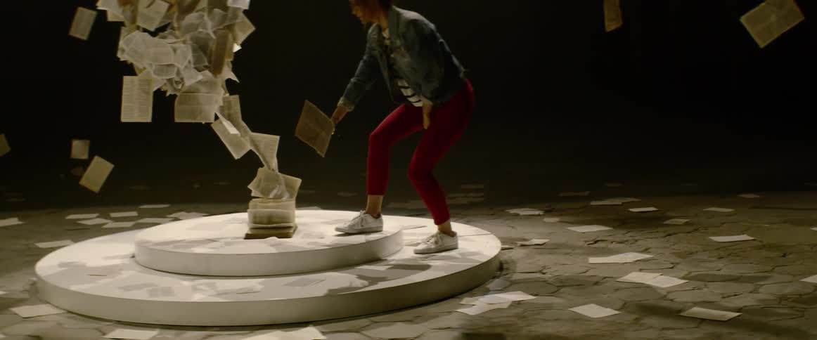 A woman with red pants walking towards an art installation