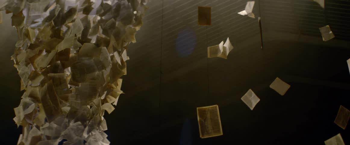 An art installation made up of book pages hangs from a ceiling
