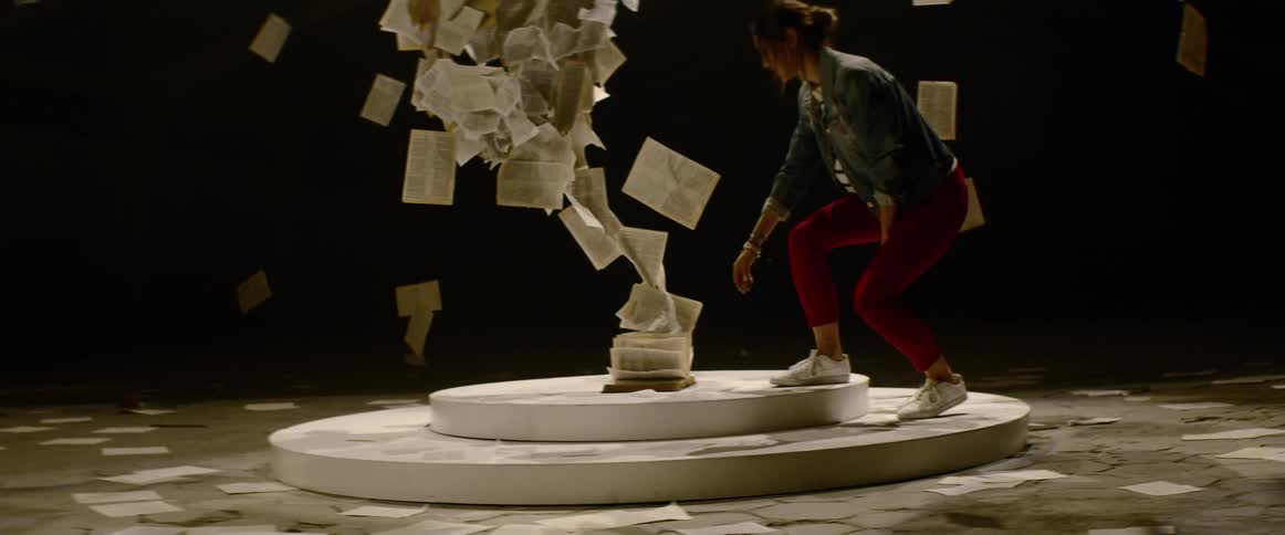 A young woman walks onto an art installation made up of floating book pages