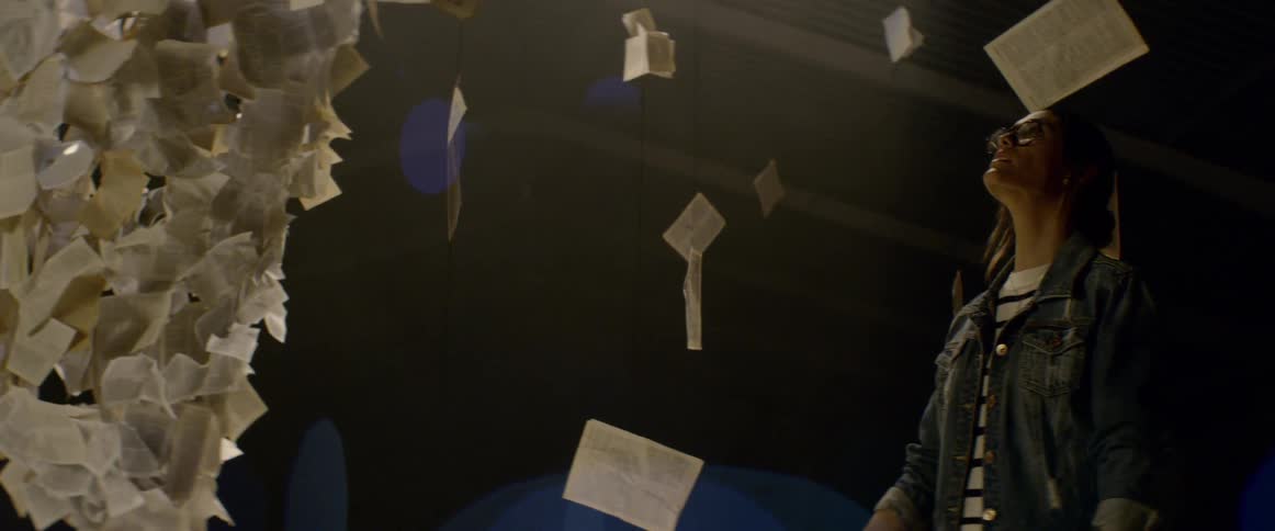 A woman walks around an art exhibition featuring floating pieces of paper